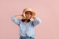 Stop this sound, please. Annoyed brunette woman covers ears by palms, has headache from loud music, wears straw hat Royalty Free Stock Photo