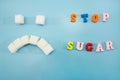 Stop sugar, text colored letters. The concept of offering diets and eating less sugar for health. Sugar harm concept. Sad face fol