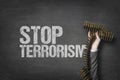 Stop terrorism text on blackboard with businessman hand holding ammunition