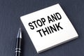 STOP AND THINK text on the sticker with pen on the black background Royalty Free Stock Photo