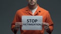 Stop victimization phrase on cardboard in hands of Caucasian prisoner, violence