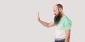 Stop, wait. Profile side view portrait of serious middle aged bald bearded man in green t-shirt standing with stop hand gesture Royalty Free Stock Photo