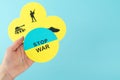 STOP WAR. Hand of a woman showing a cardboard circle with Ukrainian flag and message Stop war background of three circles with