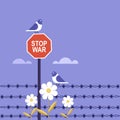 Pigeons sitting on `Stop War` signage at a fenced international border