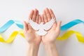 Stop the war in Ukraine concept. Top overhead view photo of female hands holding white dove on the palms over national flag on Royalty Free Stock Photo