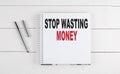 STOP WASTING MONEY text written on notebook on the wooden background Royalty Free Stock Photo