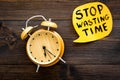 Stop wasting time hand letterng in cloud near alarm clock on dark wooden background top view copy space. Business