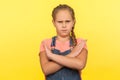 Stop, way prohibited! Portrait of little girl in denim overalls gesturing definitive No with crossed hands