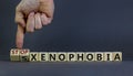 Stop xenophobia symbol. Male hand turns cubes with words `stop xenophobia`. Beautiful grey background. Business and stop