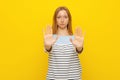 Stop. Young serious woman with fair-haired is showing stop sign with palms, stretch out arms, permission denied, prohibit gesture