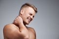 Stop when your body tells you to. Studio shot of a muscular young man experiencing neck pain against a grey background.