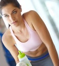 Stopping for a sip of water. A beautiful young woman sitting at the gym taking a break and having a drink of water. Royalty Free Stock Photo