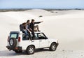 Stopping to appreciate that view. a group of friends sitting on their car while on a roadtrip.