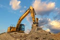 Yellow excavator at stunning fluffy clouds