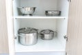 Storage of steel metal pans and other kitchenware, cookware utensils in cupboard of modern kitchen Royalty Free Stock Photo