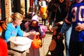 A store employee hands out treats to costumed trick or treaters in a downtown district Royalty Free Stock Photo