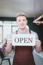 Store owner man holding open sign broad at entrance door of restaurant and coffee shop for telling customers that shop is ready to Royalty Free Stock Photo