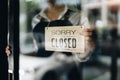 Store owner turning close sign broad through the door glass. small business owner concept. Royalty Free Stock Photo