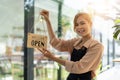 Store owner turning open sign broad through the door glass and ready to service. Happy asian female small business Royalty Free Stock Photo