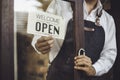 Store owner turning open sign broad through the door glass