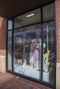 A store window with a green dress and a white and pink dress on display in a red brick buildings with a red b