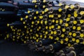 Stored many black steel pipe with heat insulation on construction site in a plastic tube wrapper lying with yellow lids pipes