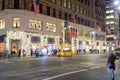 Storefront Christmas Decoration with Bright Lights at Night in Manhattan, New York City. A Taxi is About to Cross the Crossroad.