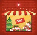 Storefront with Christmas gifts sale. Store and storefront window facade. Lighting shop window with sunblind in brick wall. Stacks