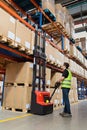 Storehouse employee in uniform working on forklift in modern automatic warehouse.Boxes are on the shelves of the warehouse.