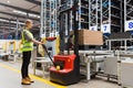 Storehouse employee in uniform working on forklift in modern automatic warehouse.Boxes are on the shelves of the warehouse.