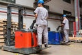Storehouse employees in uniform working on forklift in modern automatic warehouse.Boxes are on the shelves of the warehouse.