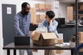 Storehouse workers discussing shipping logistics after putting client package in cardboard box Royalty Free Stock Photo