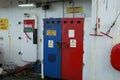Stores of oxygen and acetylene gas bottles behind the blue and red metal doors with warning stickers situated on ship.