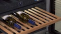 Storing bottles of wine in fridge for cooling and preserving wine. Household utensils. Close up of man demonstrating Royalty Free Stock Photo