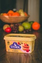 Stork baking container on top of a wooden table with healthy fruit in the background