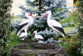 Stork family with four baby storks in a garden. Garden figurine.