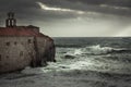 Storm with big stormy waves at coastline crashing on the walls of a medieval castle on sea shore and dark dramatic sky in fall se Royalty Free Stock Photo