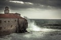 Storm with big stormy waves at coastline crashing on the walls of a medieval castle on sea shore and dark dramatic sky in fall se Royalty Free Stock Photo