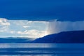 Storm cloud over lake Baikal with sun light and rain. Mountains in the fog, waves on the water, clouds and blue tones of the Royalty Free Stock Photo