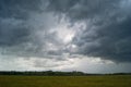 Storm cloud over yellow green fields forests and hills Royalty Free Stock Photo