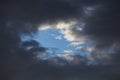 Storm clouds in the blue sky. Darkness and light. Good and evil. Heaven and hell. A piece of blue on the stormy sky background Royalty Free Stock Photo