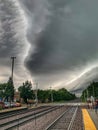 Storm clouds form patterns over metra tracks and train station platform in Chicago area