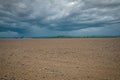 Storm clouds over farmland that is ready to be planted.