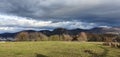 Storm clouds over the mountains, in the foreground a meadow in the sunshine Royalty Free Stock Photo