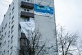 Storm damage. Big poster torned of the wall of the house after strong wind. Rescuers deal with damage