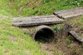 Storm drain concrete pipe covered with old dilapidated concrete tiles to be used as small improvised backyard bridge