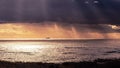 Storm on the Pacific Ocean coastline with sun-rays passing through dark clouds; Bright light shining in the background and cargo