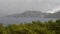 A storm with rain, thunderstorm and lightning looming on the Mediterranean Sea coast with mountains covered with forests near the