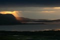 Storm sky with majestic golden rays of setting sun over sea.