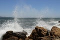 Big storm waves hitting the coastal rocks of the sea. Sunny windy day, blue sky. Splashes and foam. Storm landscape. Royalty Free Stock Photo